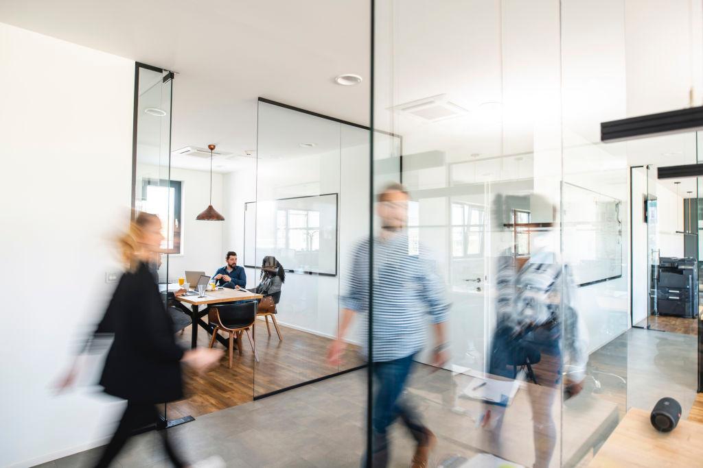 Blurred motion of energetic businesspeople on the go and project team members discussing ideas in a conference room.