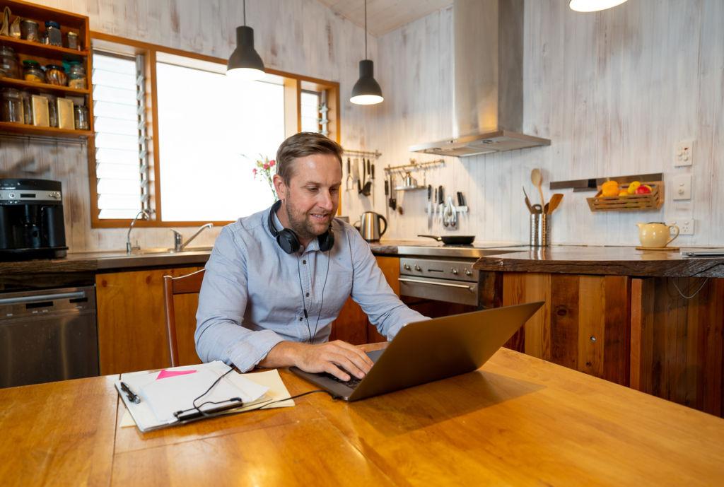 Happy business man on laptop working from home. Freelancer on computer on a video conference with employees working remotely in coronavirus Lockdown, Social Distancing and New Normal concept.