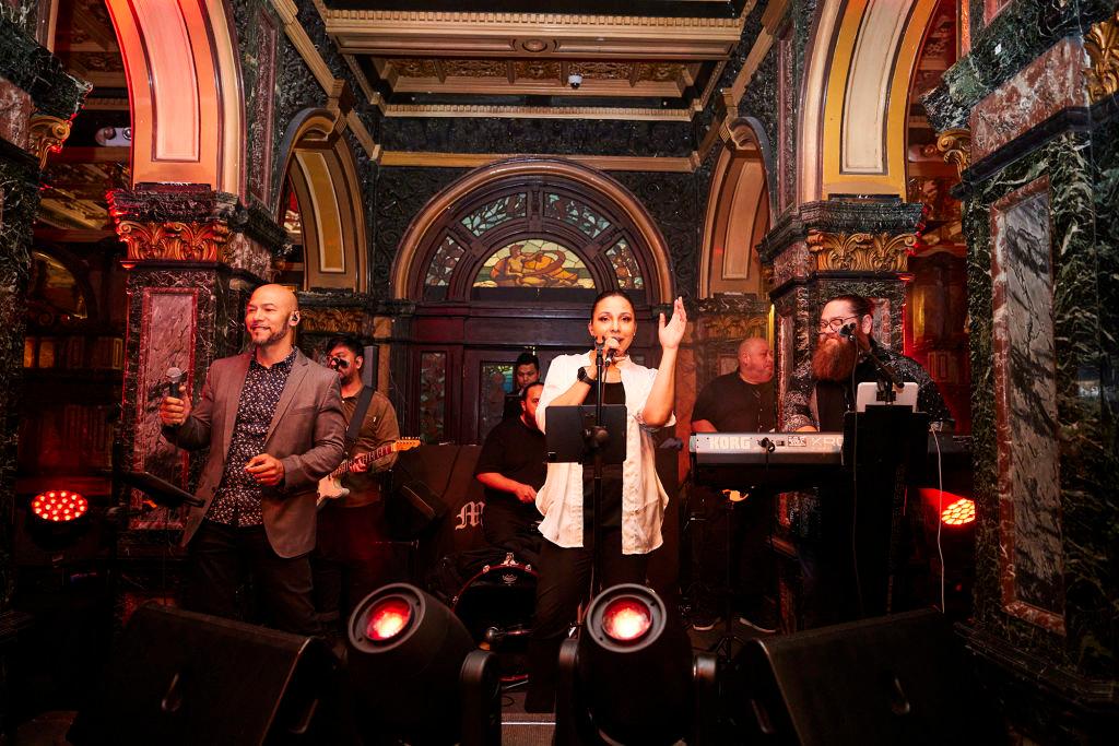 A band performs under ornate archways in a bar.